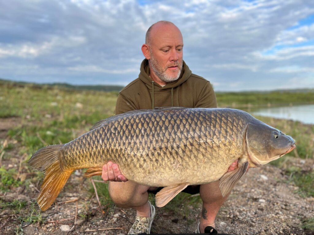 Angler holding a large carp on the shores of Last Mountain Lake
